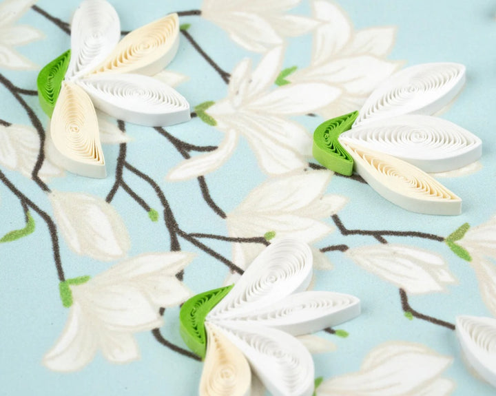 Quilled white flowers with green stems on a light blue background
