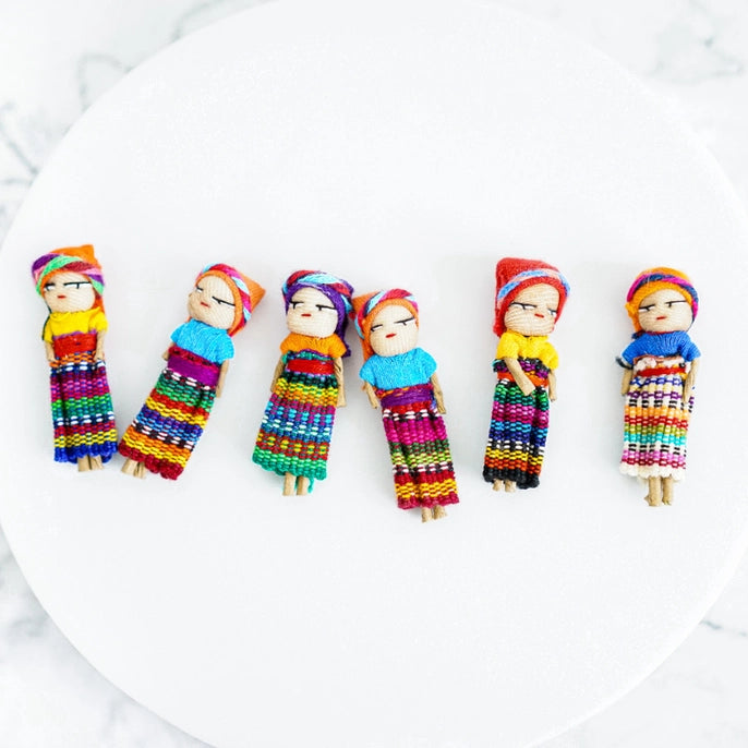Colorful handcrafted dolls with traditional attire on a white plate
