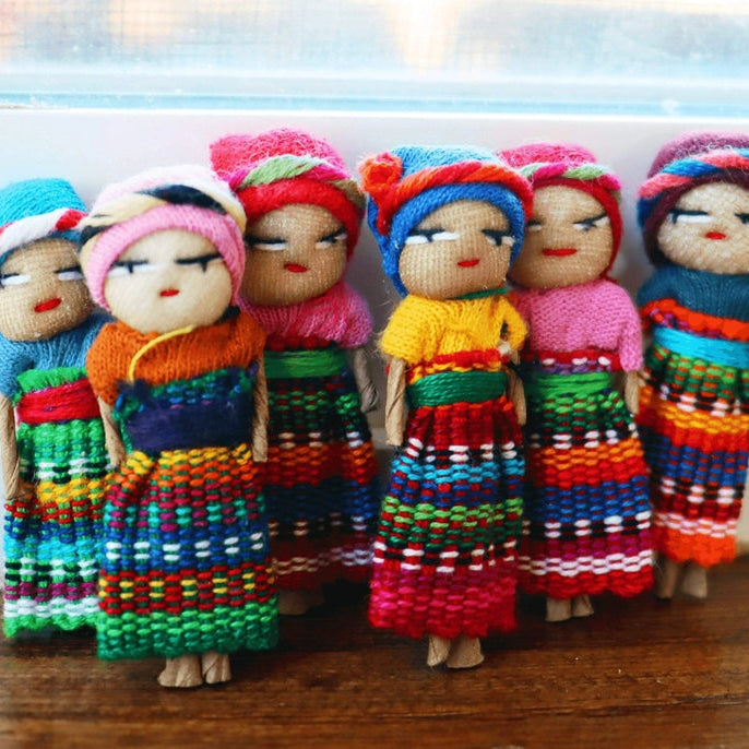Set of colorful handcrafted dolls with traditional attire on a wooden surface.