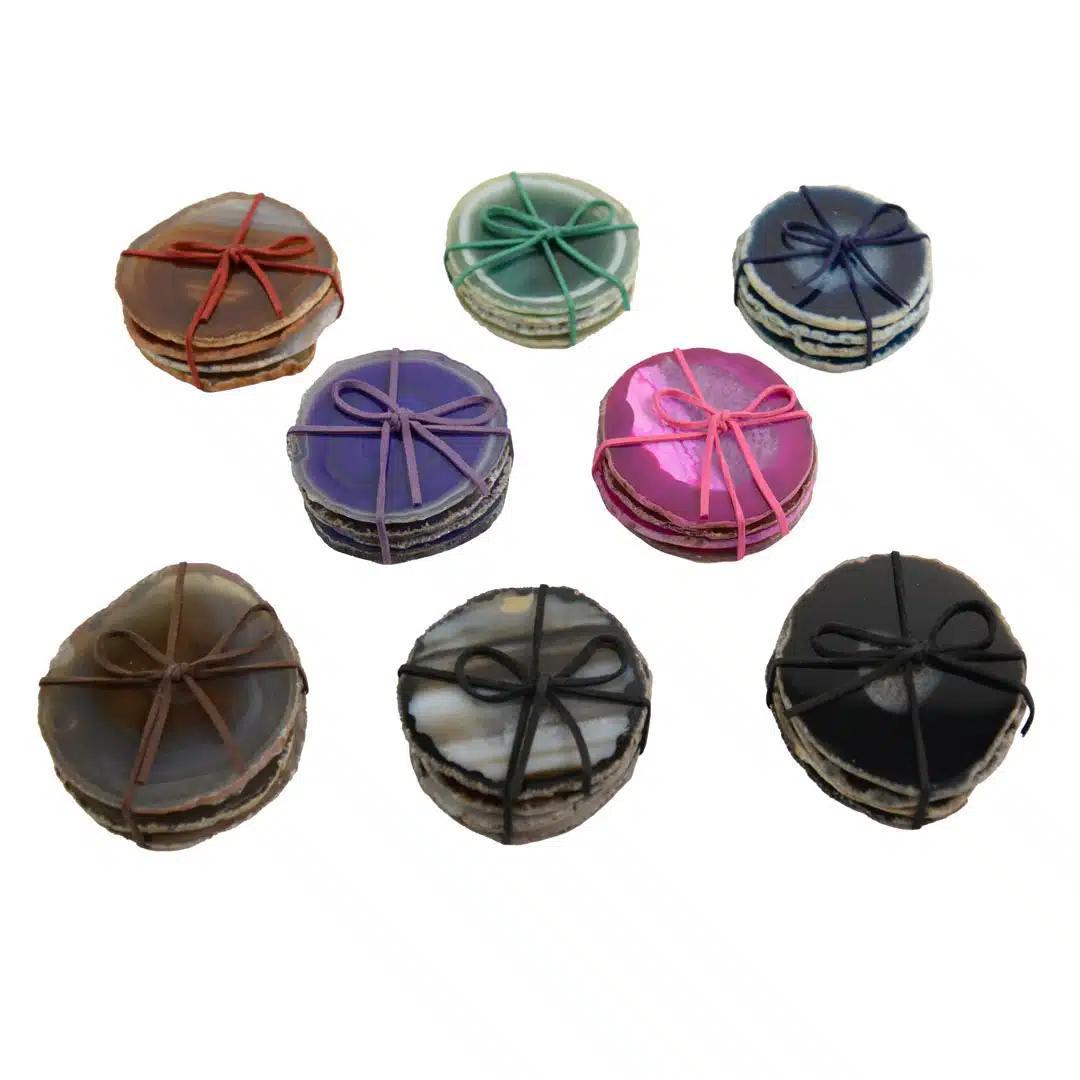 Multiple sets of colorful round agate coasters with decorative strings on a white background