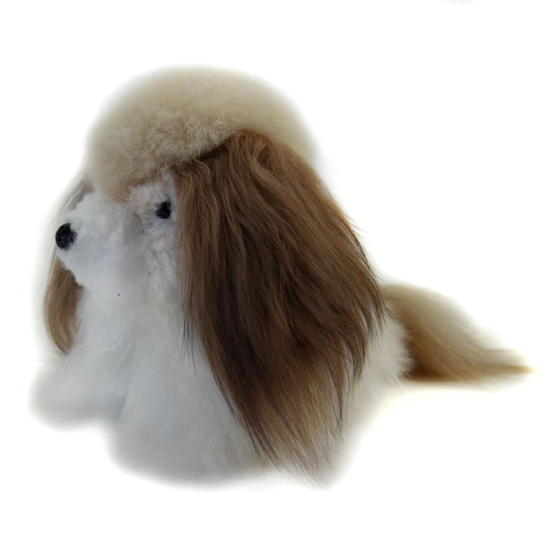 A plush toy resembling a dog with alpaca fur in beige, white, and brown colors, sitting upright.