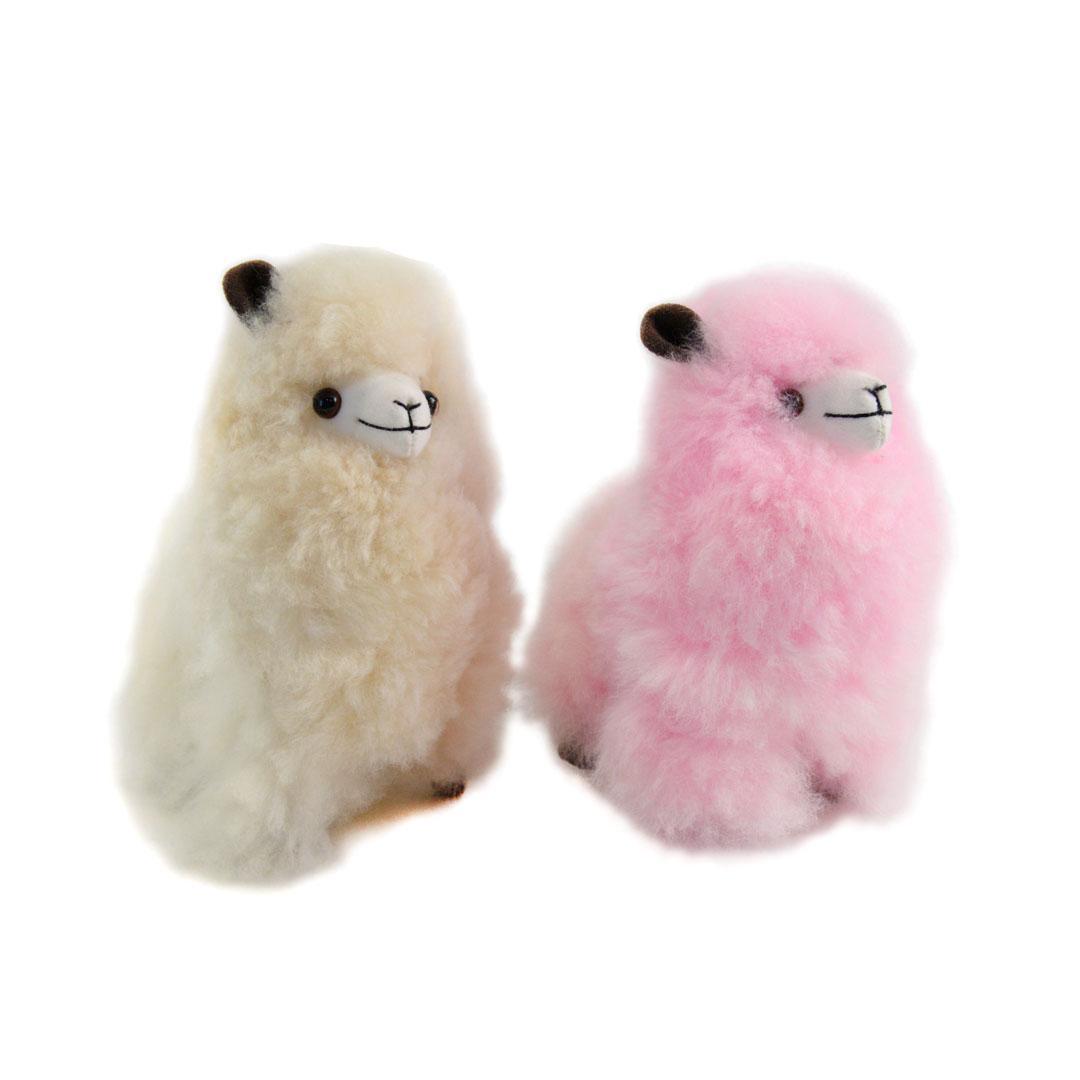 Two fluffy toy llamas Uma, one beige and one pink, on a white background