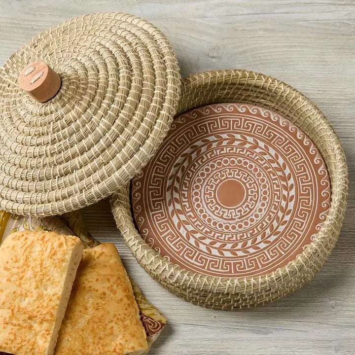 Woven basket with lid and patterned breadwarmer on a wooden surface