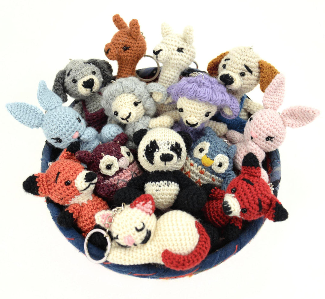 A collection of various animal-shaped crochet keychains, including a bear, panda, and other animals, displayed in a bowl.