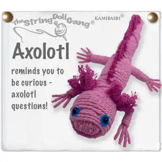 A pink string doll axolotl keychain attached to a white square sign with printed text. The sign includes the brand name TheStringDollGang and Kamibashi, along with the word 'Axolotl' and a quote.