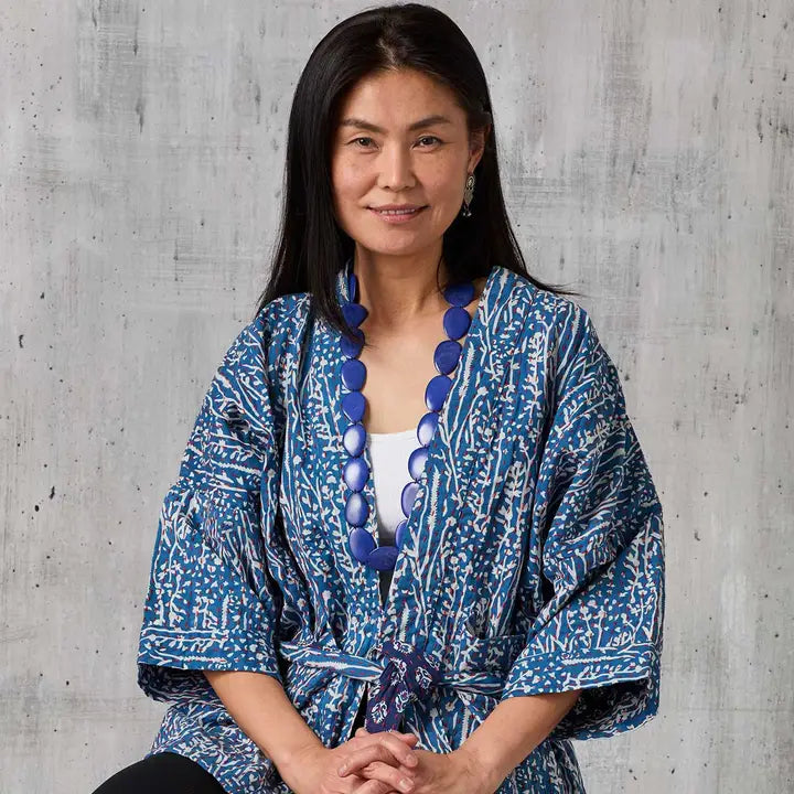Woman wearing a blue patterned kimono against a gray concrete wall