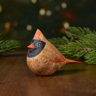 a batik female cardinal with pine branches in the background