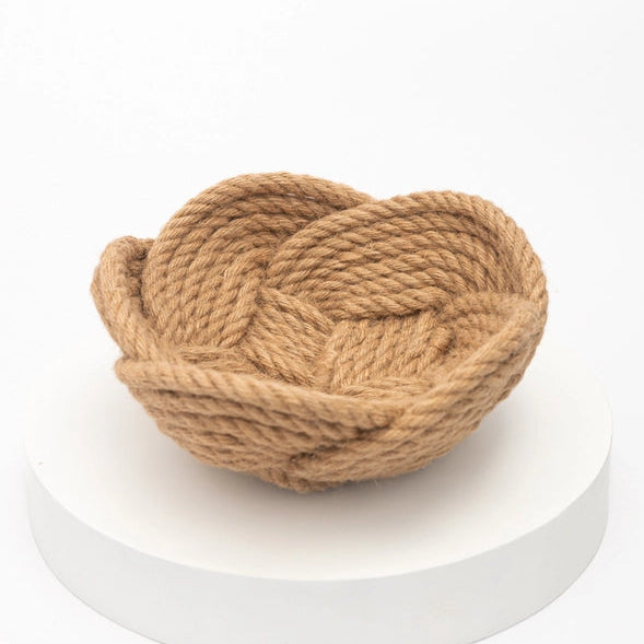 Woven rope basket on a white pedestal with a white background