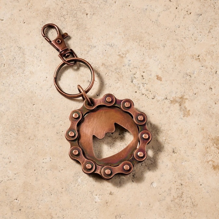 Copper keychain with a unique bike chain design on a beige background