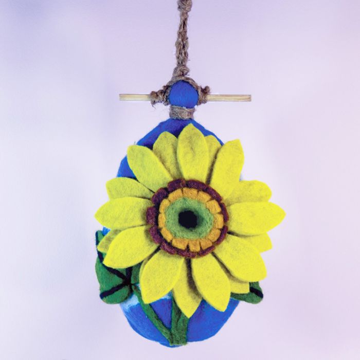 Decorative hanging birdhouse with a yellow flower on a blue base against a white background