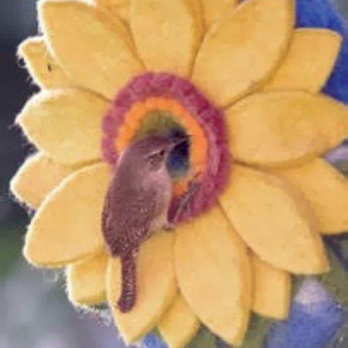 Small bird perched inside a yellow flower with a colorful center.