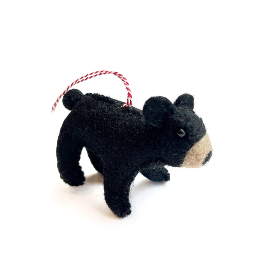 Black bear-shaped ornament with a red and white string on a white background
