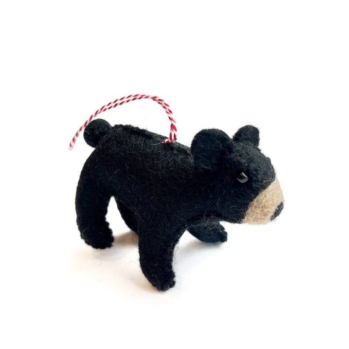 Black bear-shaped ornament with a red and white string on a white background