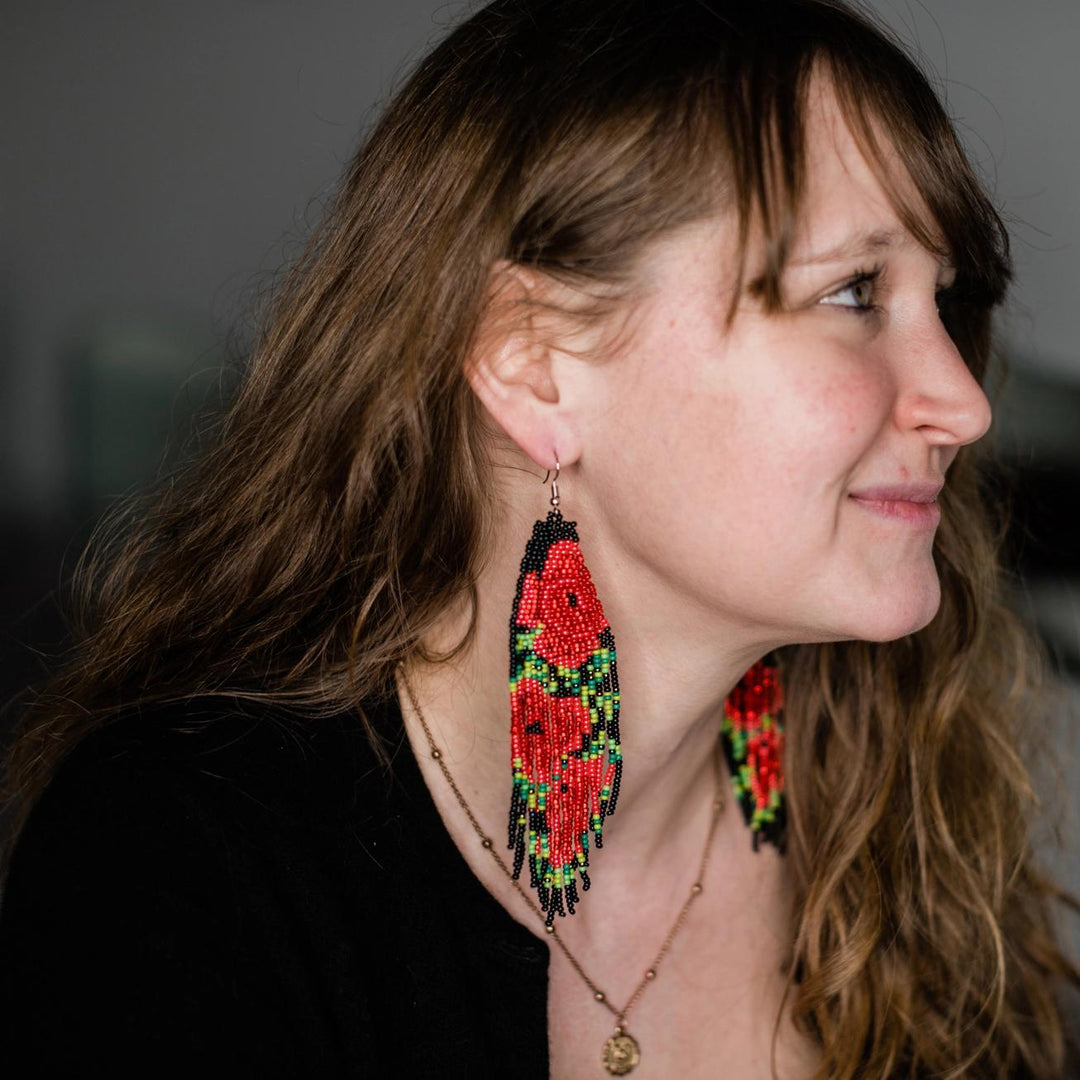 Woman wearing red rose beaded fringe earrings with a blurred background