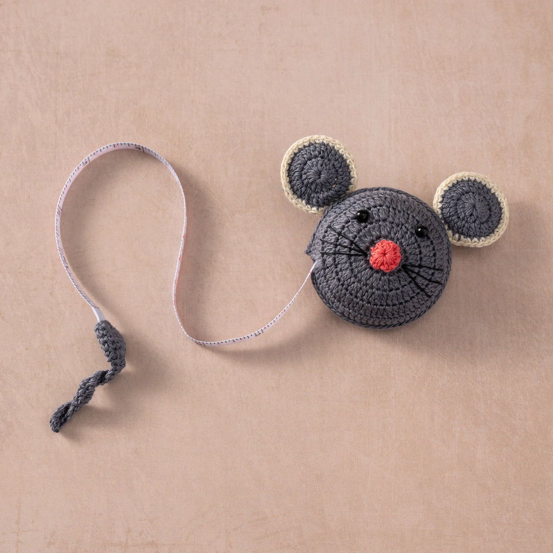 Crocheted mouse measuring tape with a red nose on a beige background