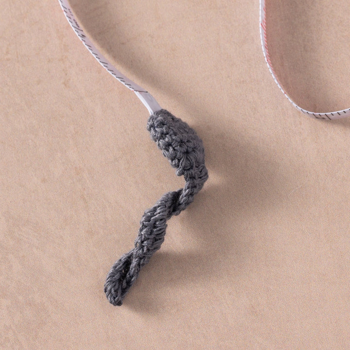 Gray braided cord mouse tail on a beige background