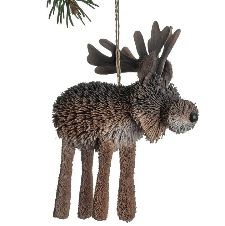 A rustic moose-shaped hanging ornament made from textured brown and gray buri pod, suspended by a string from a pine branch against a white background.