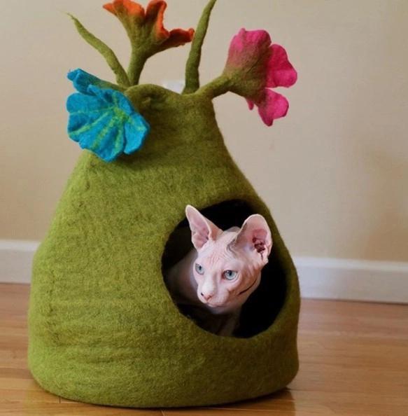 Green felted bouquet pet house with floral decorations on a wooden floor.