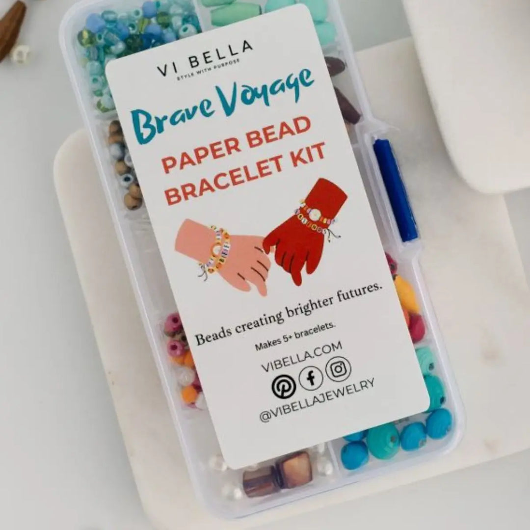 A clear plastic container holding a paper bead bracelet kit with colorful beads and a large white label reading 'VI BELLA Brave Voyage Paper Bead Bracelet Kit.' No person, animal, or real environment is the focus; this is a clean product shot, so subject_type is Product/Packaging.