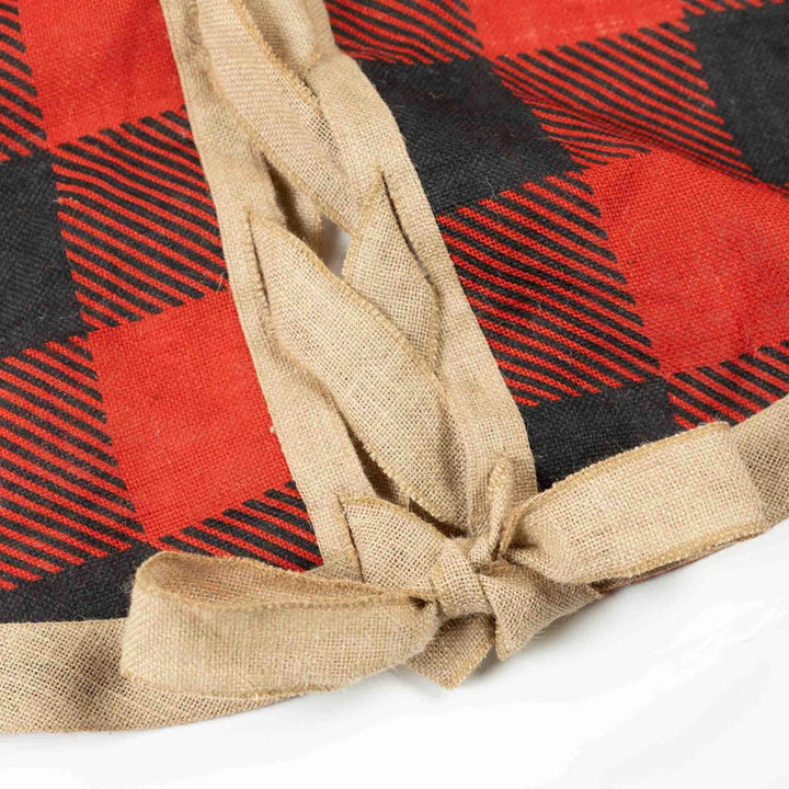 Red and black plaid fabric with a beige ribbon tied around it on a white background
