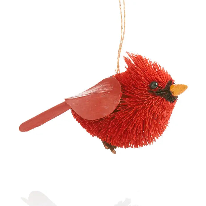 A red cardinal bird hanging ornament made of textured red bristles, with a small yellow beak, black eye, and a natural twine hanger, shown against a plain white background.