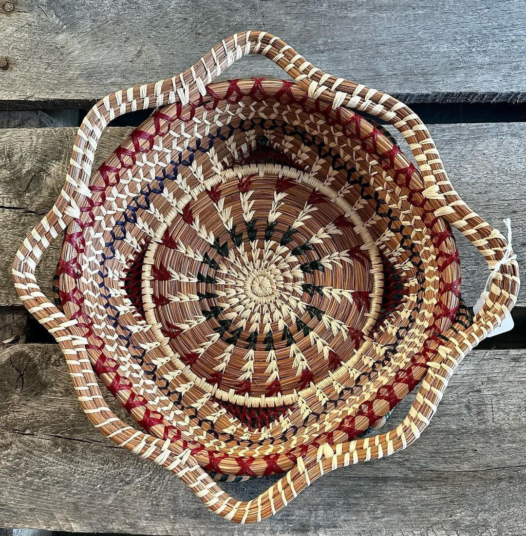 Handwoven basket with a spiral pattern and handles on a wooden surface