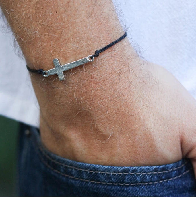 Silver cross bracelet on a wrist with a blurred background