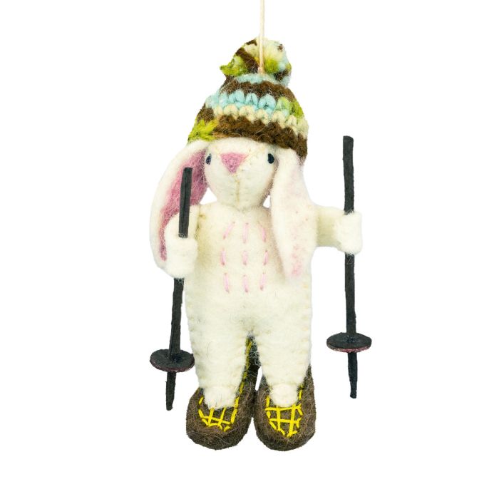 felted rabbit ornament wearing a knitted hat and holding ski poles on a white background