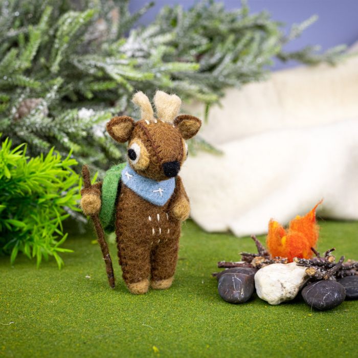 deer ornament with a backpack and staff near a campfire and greenery