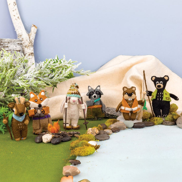 Set of forest animal ornaments in a natural setting with trees and rocks.