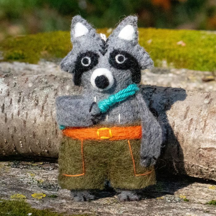 Felted raccoon ornament with a rope and orange belt on a natural background