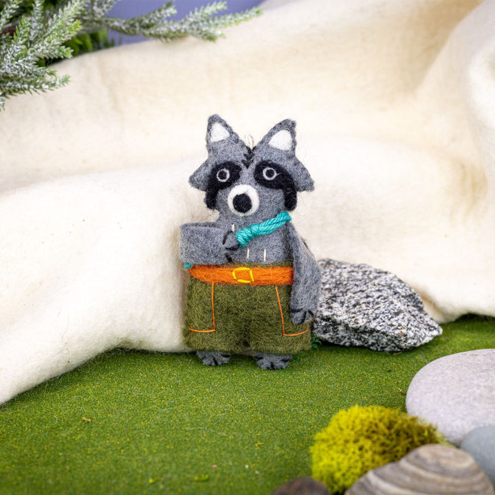 felted raccoon ornament with a rope and shorts in a natural setting