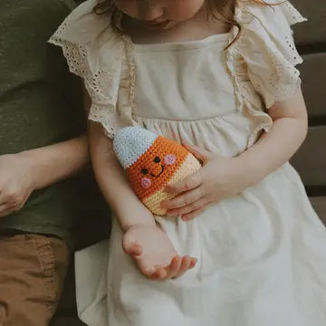 Child holding a crocheted candy corn toy on a soft background