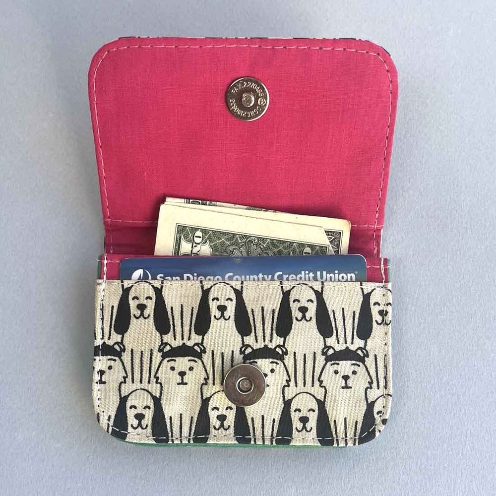 Pink wallet with dog patterned flap on a light gray background