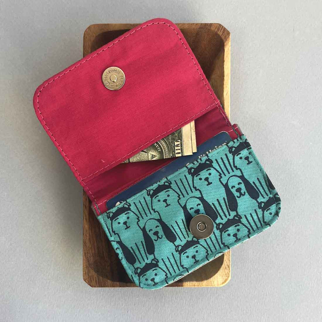 Two wallets, one red and one with a cat pattern, on a wooden block.