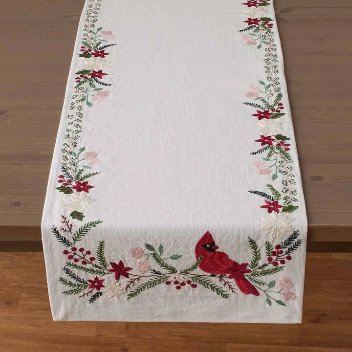 a table runner with cardinals and woodland greenery on a brown wooden table.