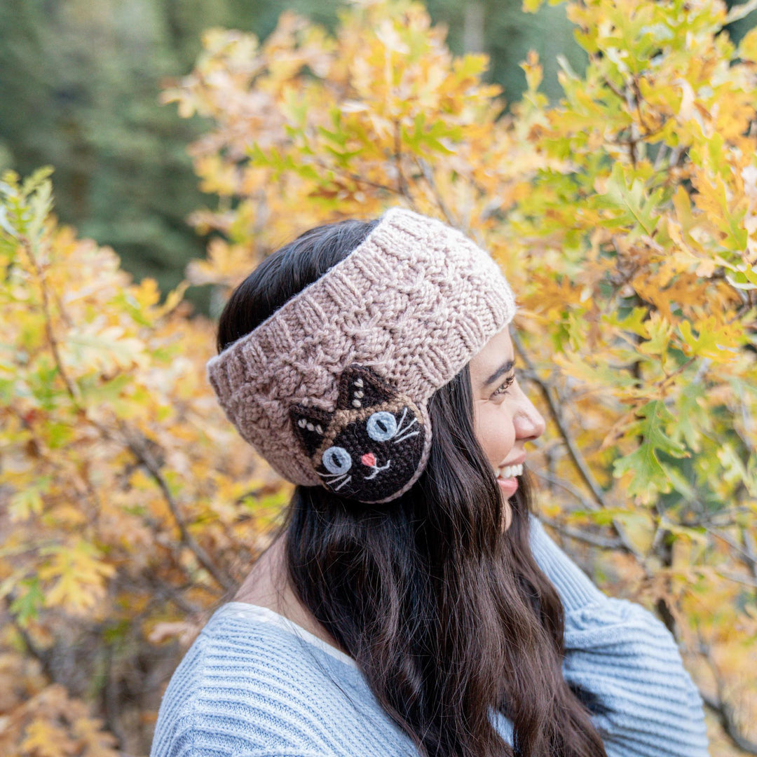 Woman wearing a knitted headband with a cat design in an autumn setting