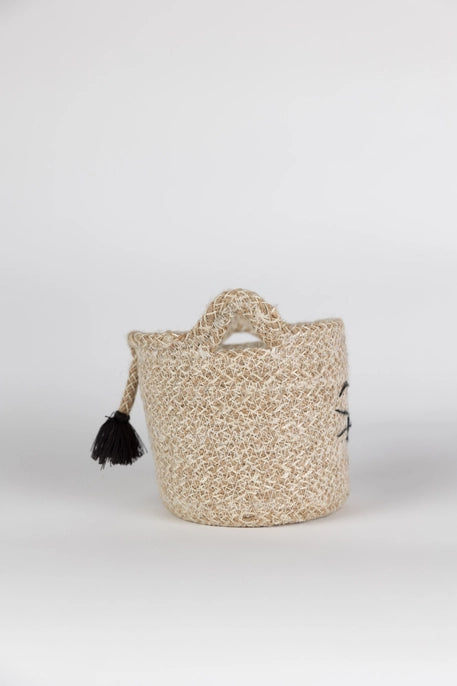 Woven basket with handles and tassels on a white background