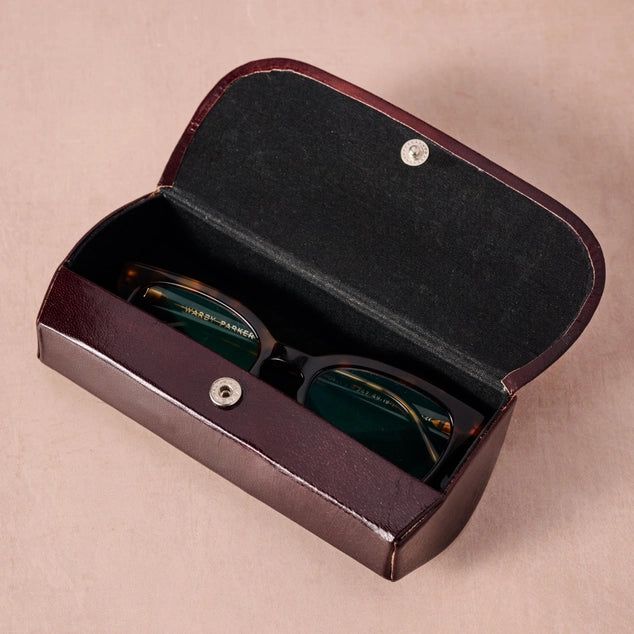 Sunglasses in a black leather case on a beige background