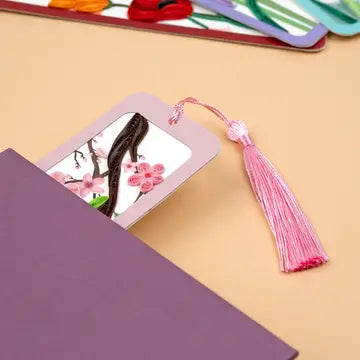 Purple notebook with a pink bookmark featuring a cherry blossom design on a beige background