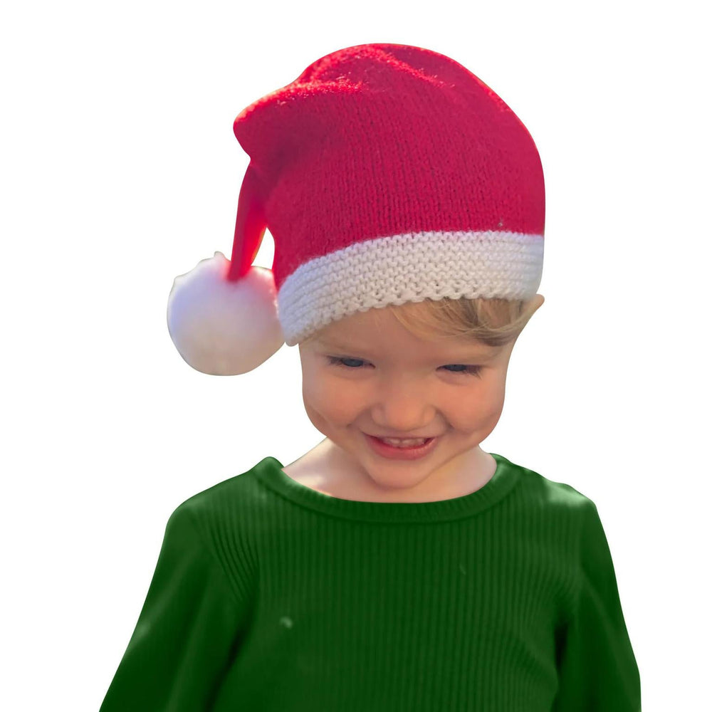 Child wearing a red and white Santa hat and green sweater on a white background