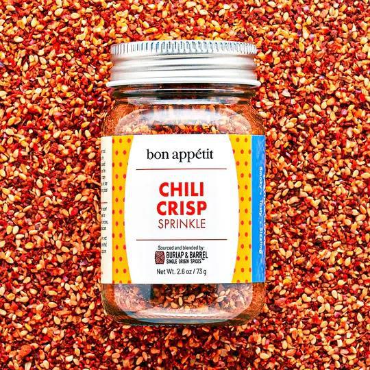 Jar of Chili Crisp Sprinkle seasoning on a bed of red chili flakes