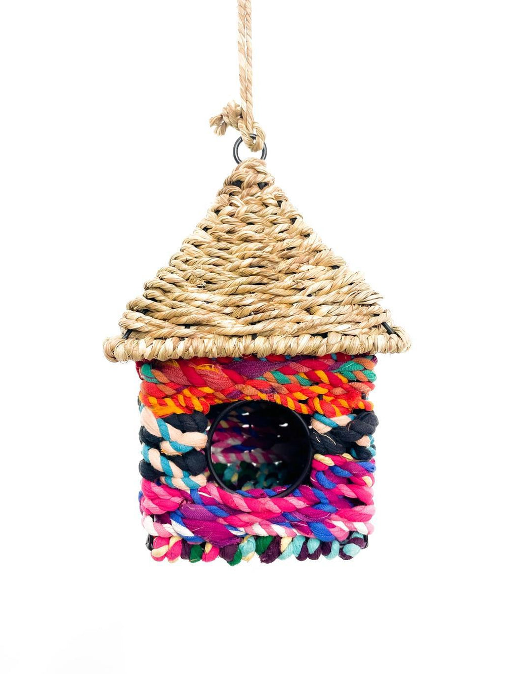 A colorful handcrafted birdhouse made from seagrass and sari fabric, with a variety of colors and patterns.