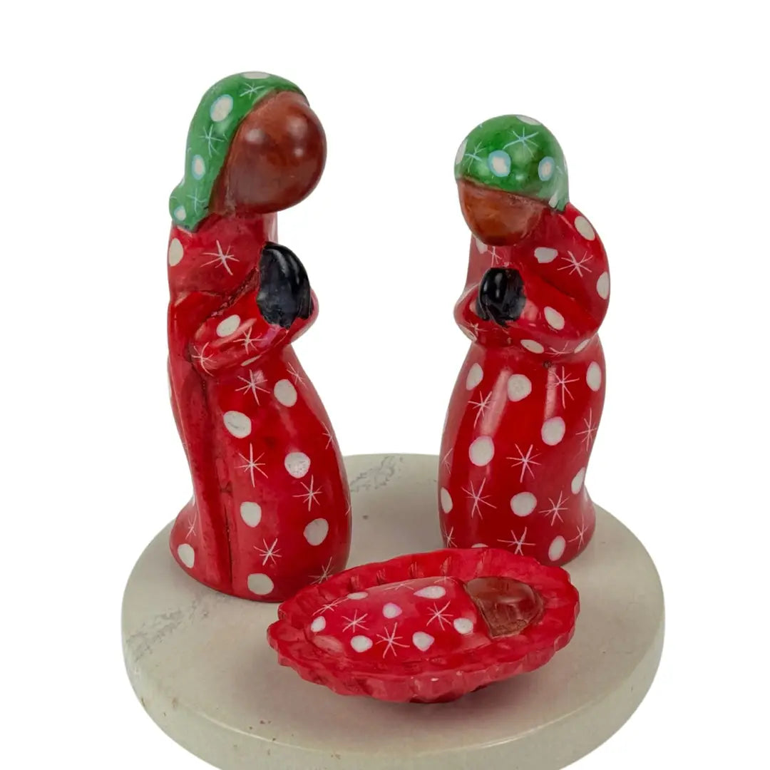 A small soapstone nativity with Mary, Joseph and baby Jesus and a stone platform against a plain white background.