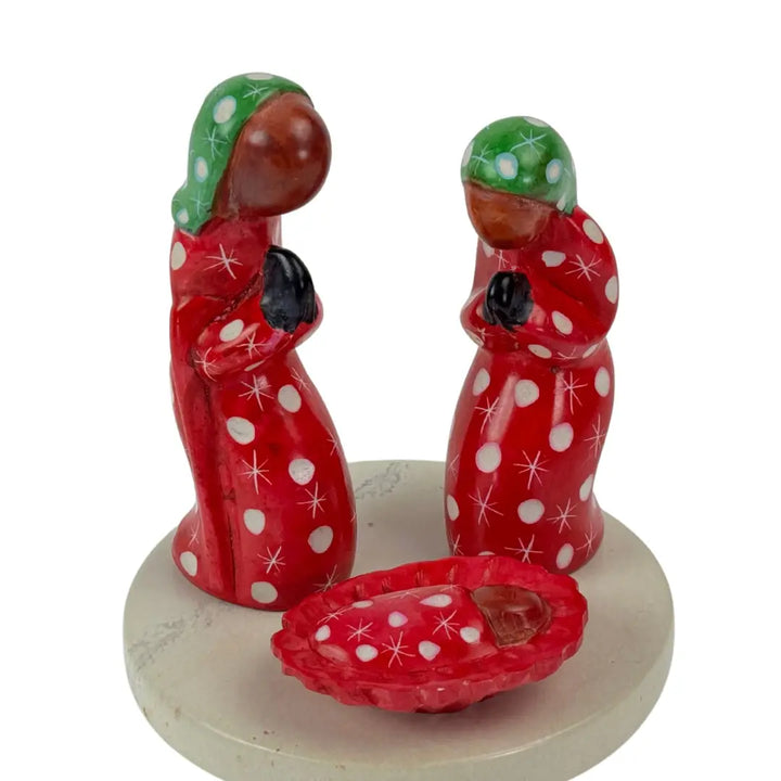 A small soapstone nativity with Mary, Joseph and baby Jesus and a stone platform against a plain white background.