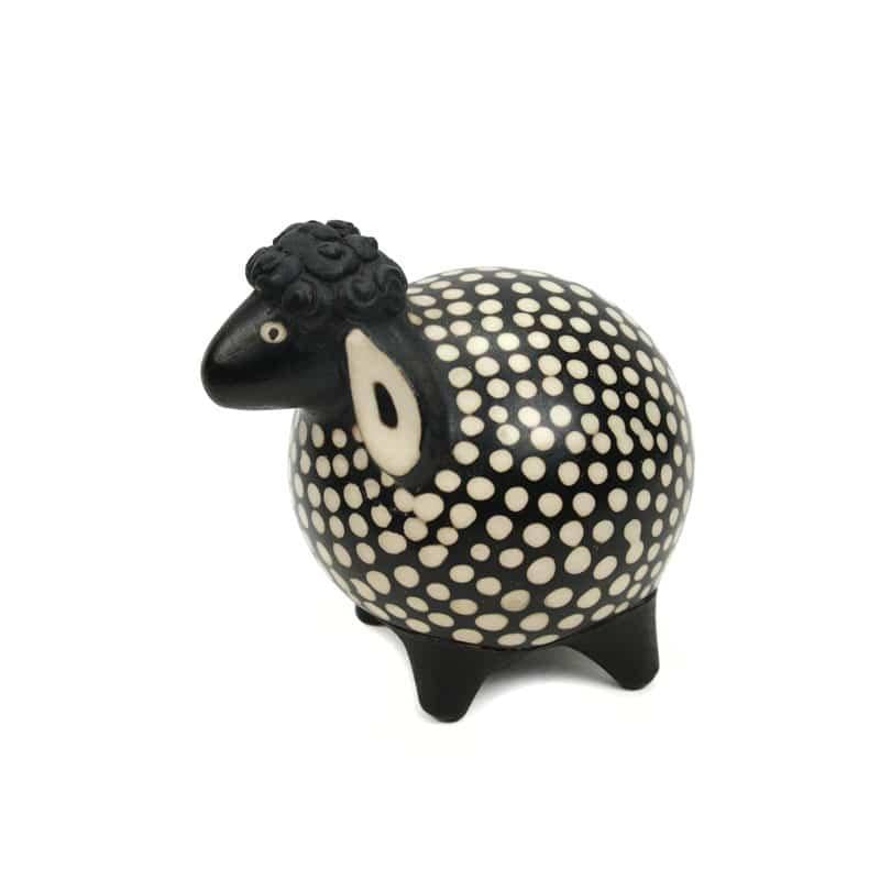 A ceramic sculpture of a sheep with a black and white pattern and polka dots.