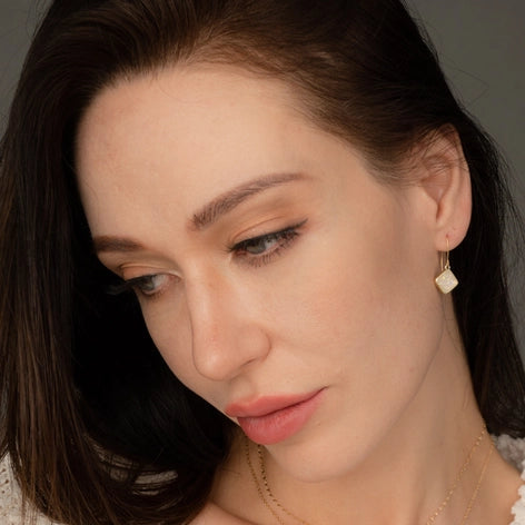 Woman wearing earrings and a necklace with a neutral background