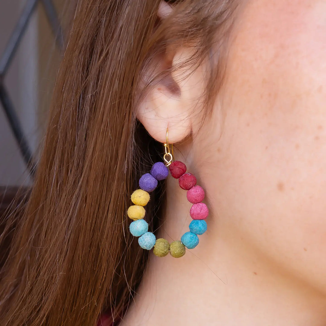 Close-up of a colorful Kantha hoop earring worn by a person