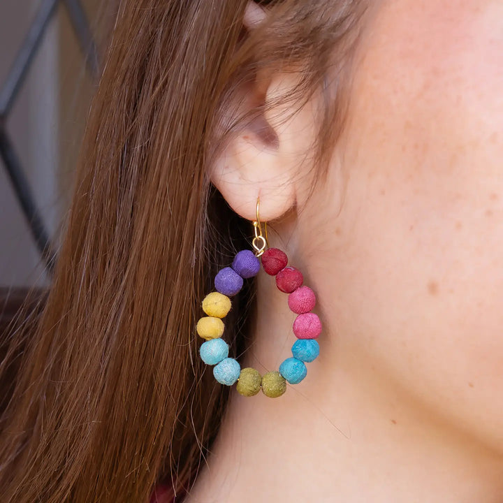 Close-up of a colorful Kantha hoop earring worn by a person
