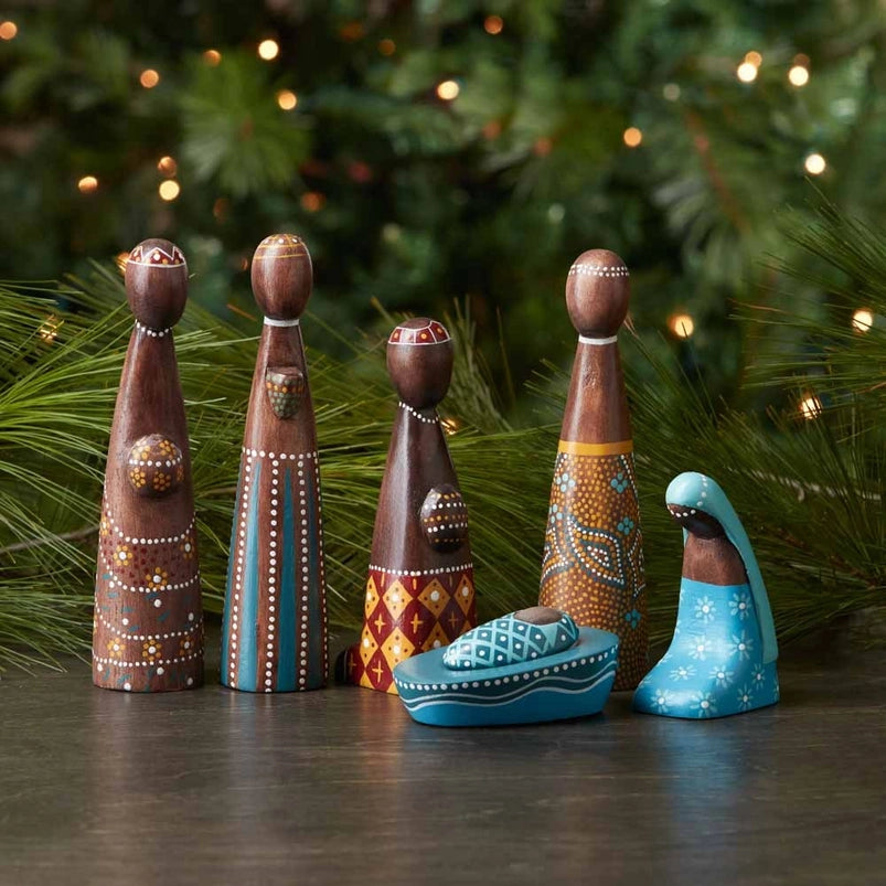 Decorative nativity scene figures with a Christmas tree in the background